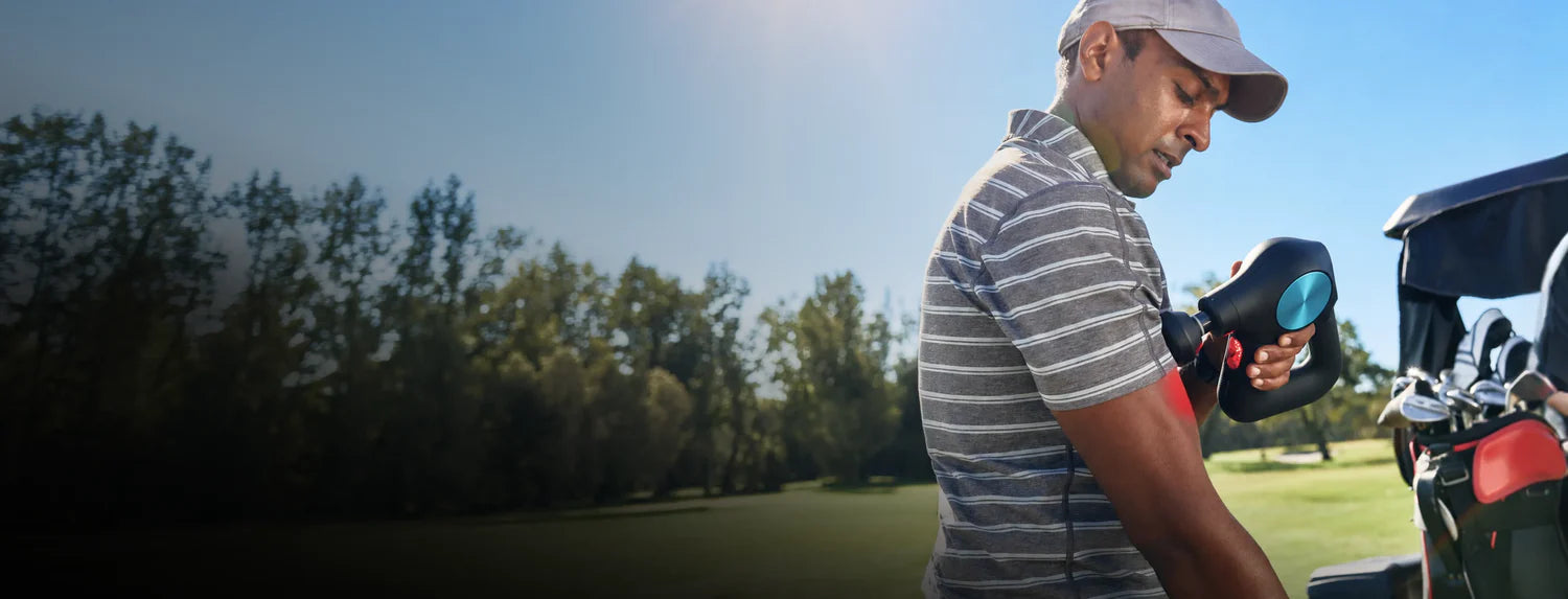 Golfer using a portable percussion massage gun to relax arm and shoulder muscles after golf practice.